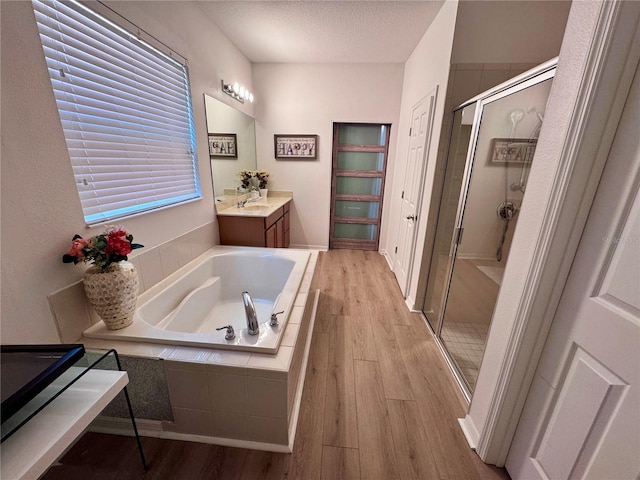 2691 Cypress Tree Trl, Saint Cloud, FL 34772 - bathroom featuring a stall shower, wood finished floors, a bath, vanity, and a textured ceiling