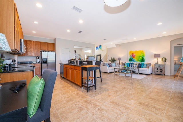 389 Yellow Snapdragon Dr, Davenport, FL 33837 - kitchen with stainless steel appliances, open floor plan, dark countertops, brown cabinets, and recessed lighting