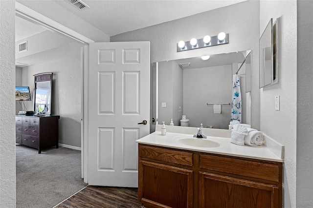 4551 Jonafree Ln Unit 103, Kissimmee, FL 34746 - bathroom with a textured wall, vanity, wood finished floors, curtained shower, and a textured ceiling