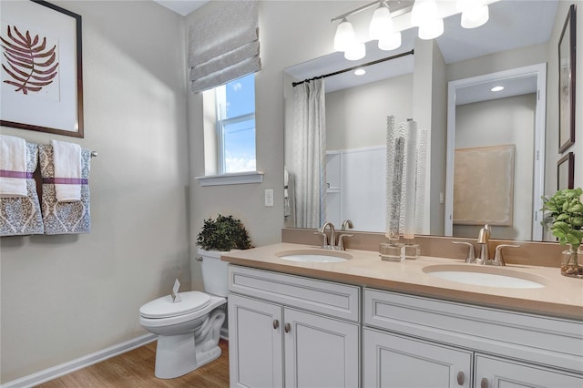 full bathroom featuring toilet, wood finished floors, double vanity, and baseboards