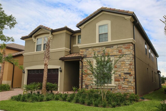 2147 Tripoli Ct, Kissimmee, FL 34747 - view of front of house featuring a garage, stucco siding, stone siding, and a tiled roof