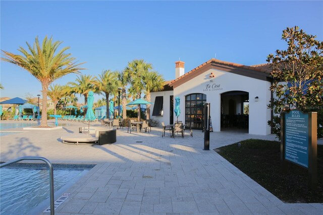 2147 Tripoli Ct, Kissimmee, FL 34747 - rear view of property featuring a chimney, stucco siding, a tiled roof, and a community pool