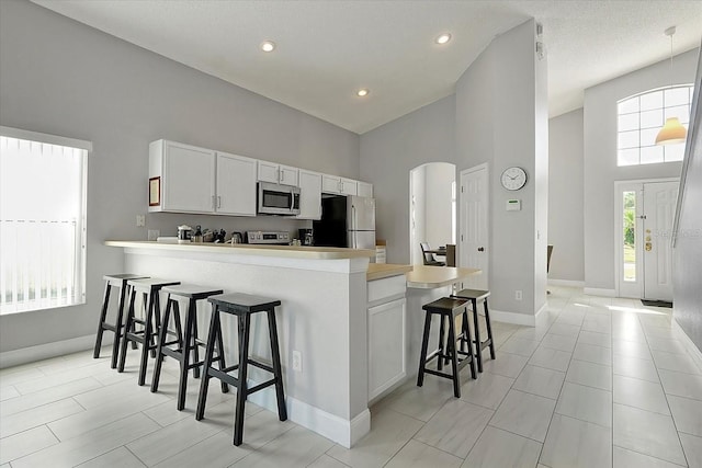 553 Bailey Cir, Davenport, FL 33897 - kitchen featuring stainless steel appliances, a high ceiling, arched walkways, a peninsula, and a breakfast bar