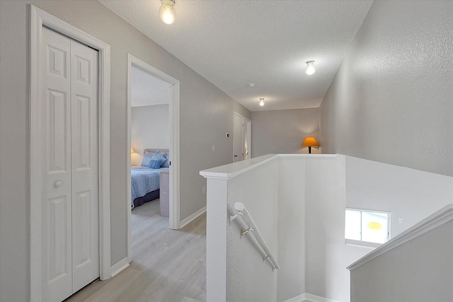 553 Bailey Cir, Davenport, FL 33897 - corridor featuring an upstairs landing, light wood finished floors, a textured ceiling, and baseboards