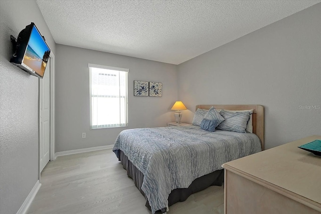 553 Bailey Cir, Davenport, FL 33897 - bedroom featuring light wood-style floors, a textured ceiling, and baseboards