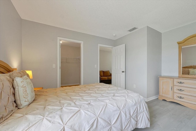 553 Bailey Cir, Davenport, FL 33897 - bedroom with light wood-type flooring, a spacious closet, a textured ceiling, baseboards, and a closet