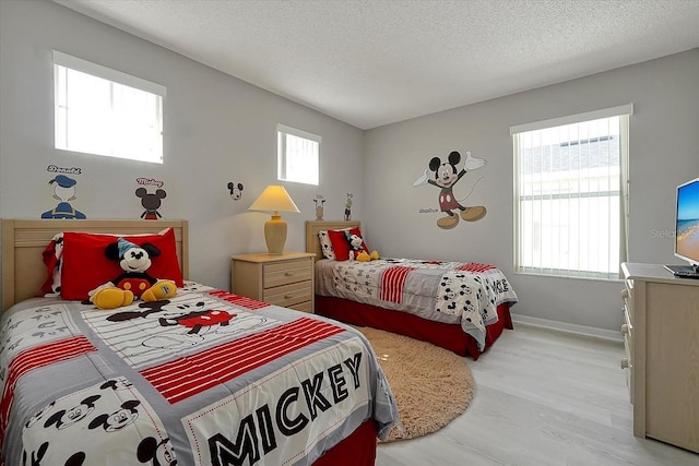 553 Bailey Cir, Davenport, FL 33897 - bedroom with multiple windows, light wood finished floors, a textured ceiling, and baseboards