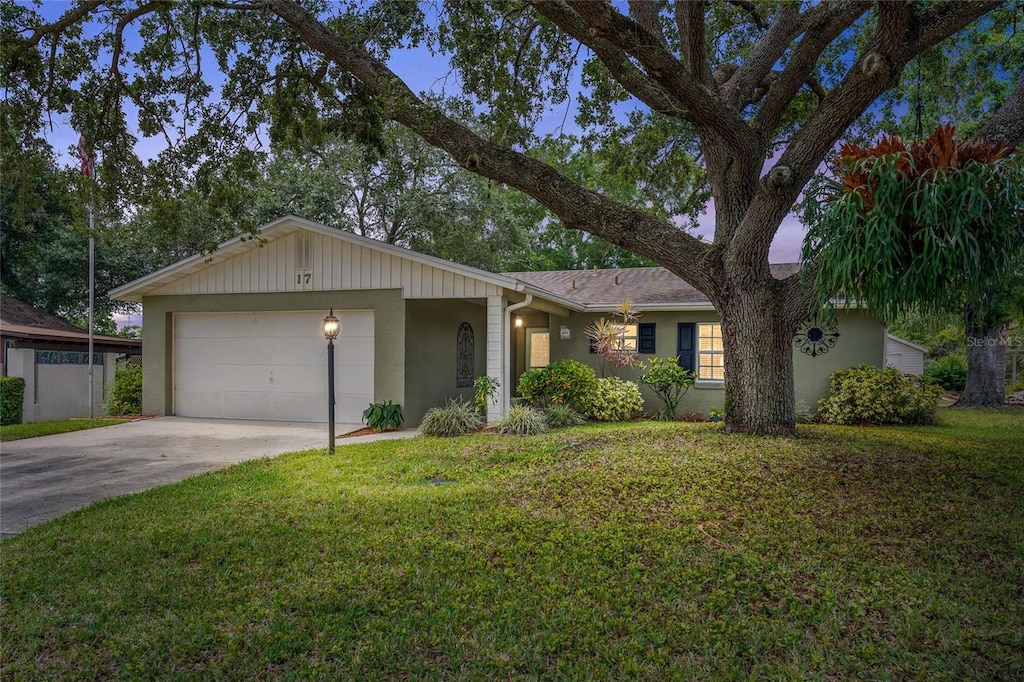 17 Juniper Dr, Davenport, FL 33837 - ranch-style house featuring stucco siding, an attached garage, a front lawn, and concrete driveway