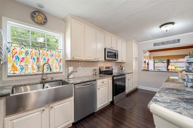 kitchen featuring appliances with stainless steel finishes, dark wood finished floors, a sink, tasteful backsplash, and a textured ceiling