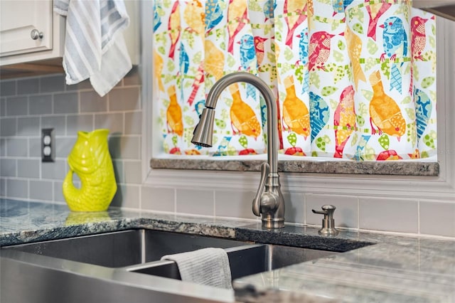 kitchen view of tasteful backsplash, a sink, and white cabinetry
