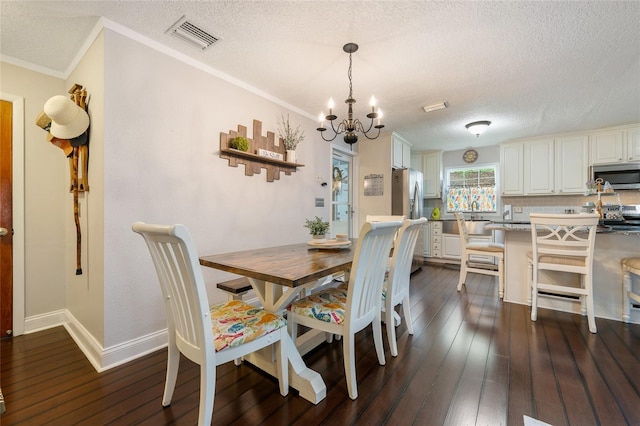 dining room with a textured ceiling, a chandelier, dark wood finished floors, ornamental molding, and baseboards