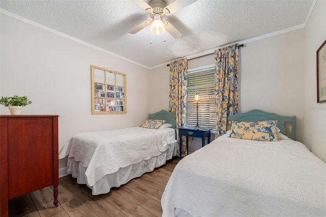 bedroom featuring wood finished floors, a textured ceiling, ornamental molding, and a ceiling fan
