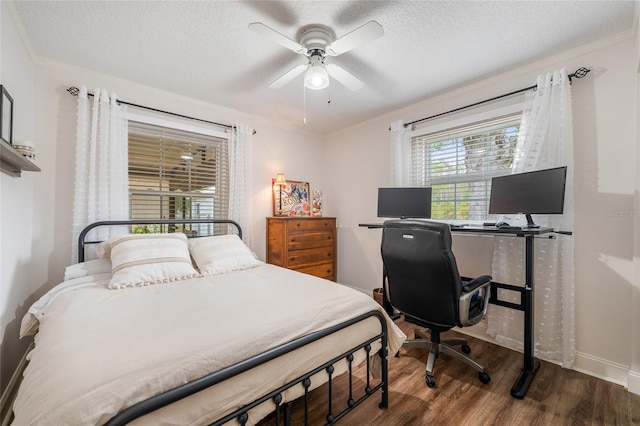 bedroom featuring wood finished floors, a textured ceiling, an office area, a ceiling fan, and baseboards