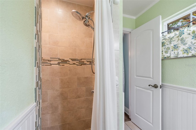 full bath with tiled shower, ornamental molding, and a wainscoted wall