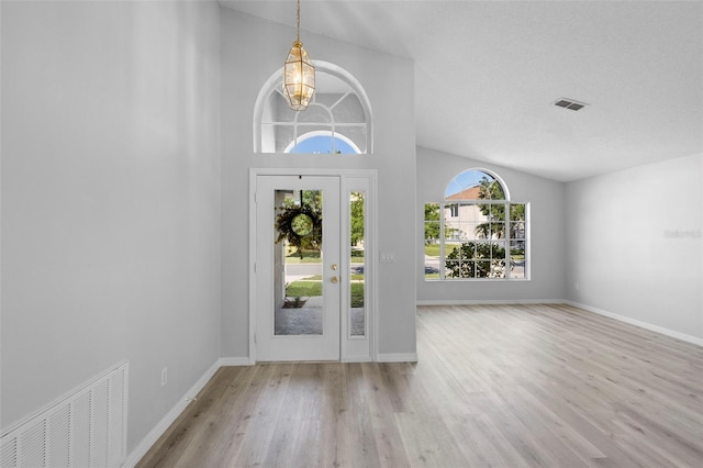foyer featuring a chandelier, wood finished floors, lofted ceiling, and baseboards