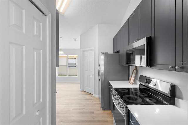 kitchen with stainless steel appliances, light wood-type flooring, light countertops, a textured ceiling, and baseboards