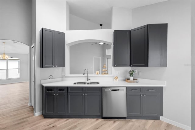 kitchen featuring dishwasher, a sink, arched walkways, light countertops, and light wood-type flooring