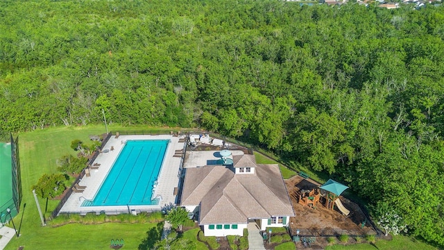 aerial view of property and surrounding area featuring a forest and a pool
