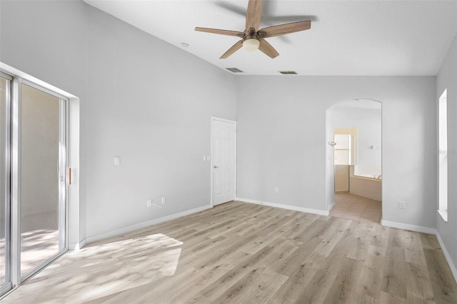 unfurnished bedroom with arched walkways, light wood-style floors, access to outside, ensuite bathroom, and baseboards