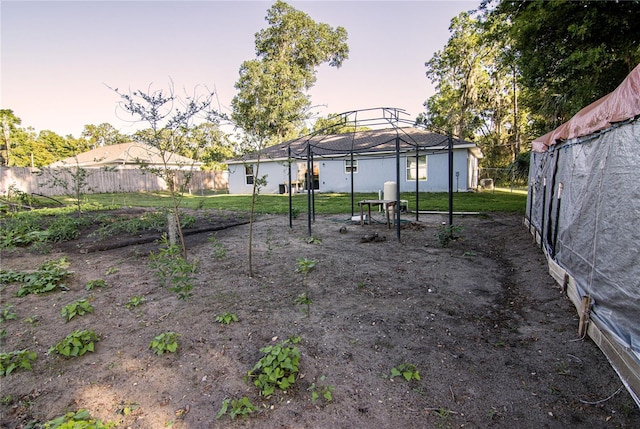 yard at dusk featuring fence and a gazebo