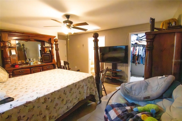 bedroom with light tile patterned flooring, a spacious closet, a ceiling fan, and ensuite bath