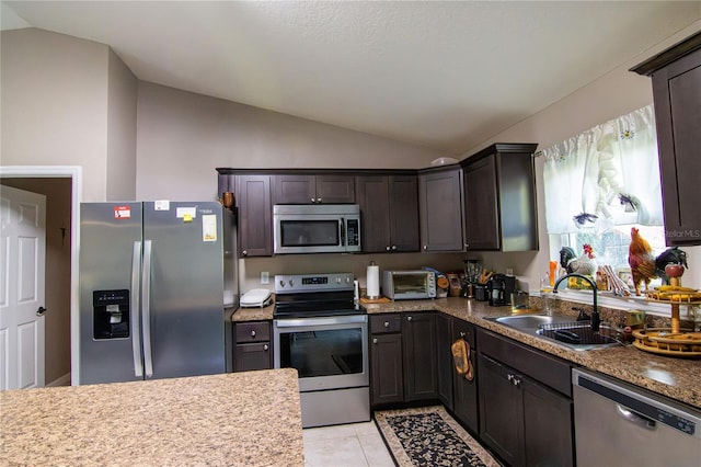 kitchen with stainless steel appliances, lofted ceiling, a sink, dark brown cabinetry, and light tile patterned floors