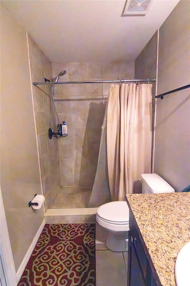 bathroom featuring toilet, tiled shower, and vanity