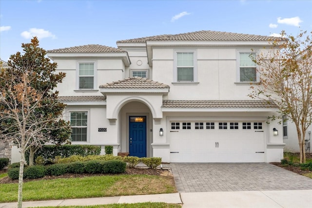 9020 Stinger Dr, Davenport, FL 33896 - view of front of property with decorative driveway, a tile roof, stucco siding, and an attached garage