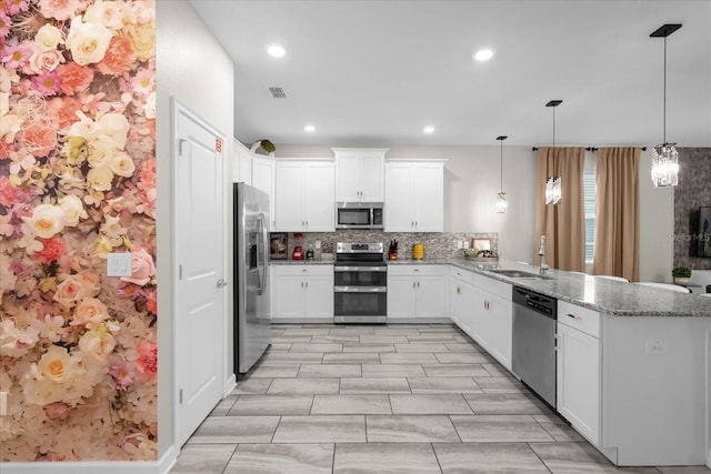 9020 Stinger Dr, Davenport, FL 33896 - kitchen featuring appliances with stainless steel finishes, a peninsula, a sink, tasteful backsplash, and white cabinetry
