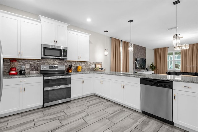 9020 Stinger Dr, Davenport, FL 33896 - kitchen with stainless steel appliances, a sink, tasteful backsplash, white cabinets, and pendant lighting