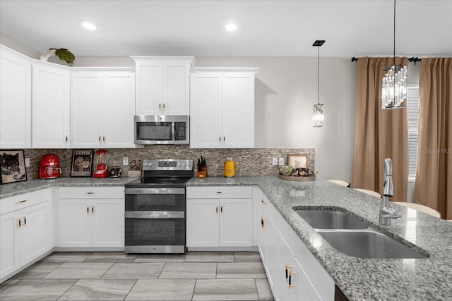 9020 Stinger Dr, Davenport, FL 33896 - kitchen featuring appliances with stainless steel finishes, a sink, backsplash, white cabinetry, and light stone counters