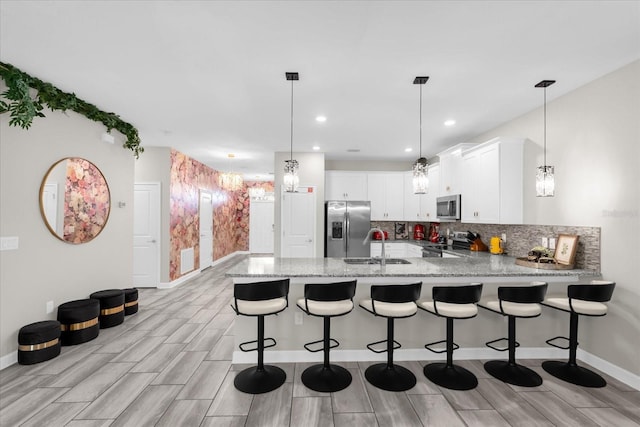 9020 Stinger Dr, Davenport, FL 33896 - kitchen with appliances with stainless steel finishes, a peninsula, a sink, backsplash, and light stone countertops
