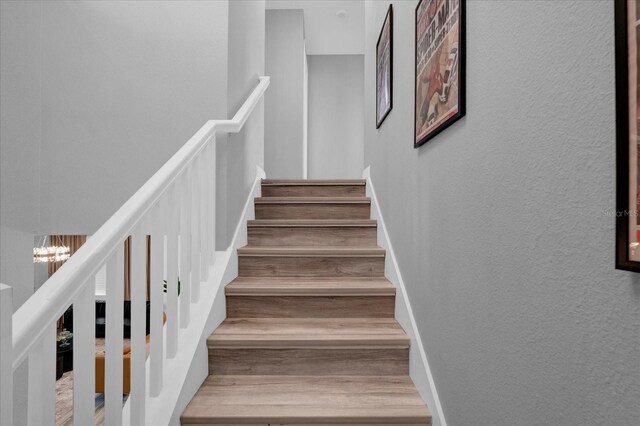 9020 Stinger Dr, Davenport, FL 33896 - stairs featuring wood finished floors, a chandelier, and a textured wall