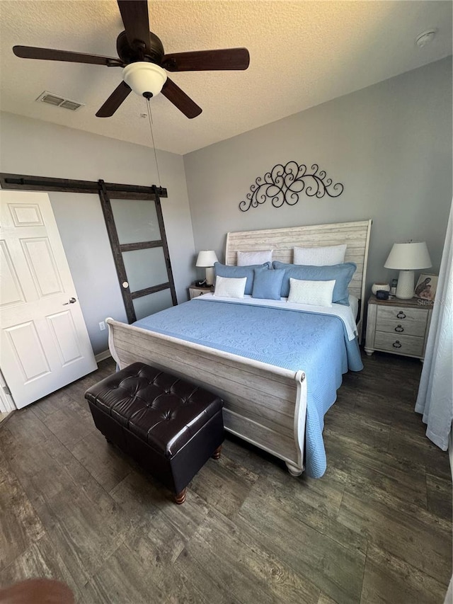 2289 Seven Oaks Dr, Saint Cloud, FL 34772 - bedroom featuring wood finished floors, a barn door, a textured ceiling, and ceiling fan