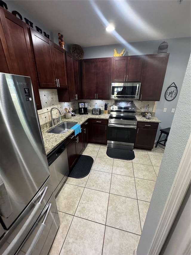 2289 Seven Oaks Dr, Saint Cloud, FL 34772 - kitchen featuring appliances with stainless steel finishes, a sink, light stone countertops, light tile patterned flooring, and backsplash