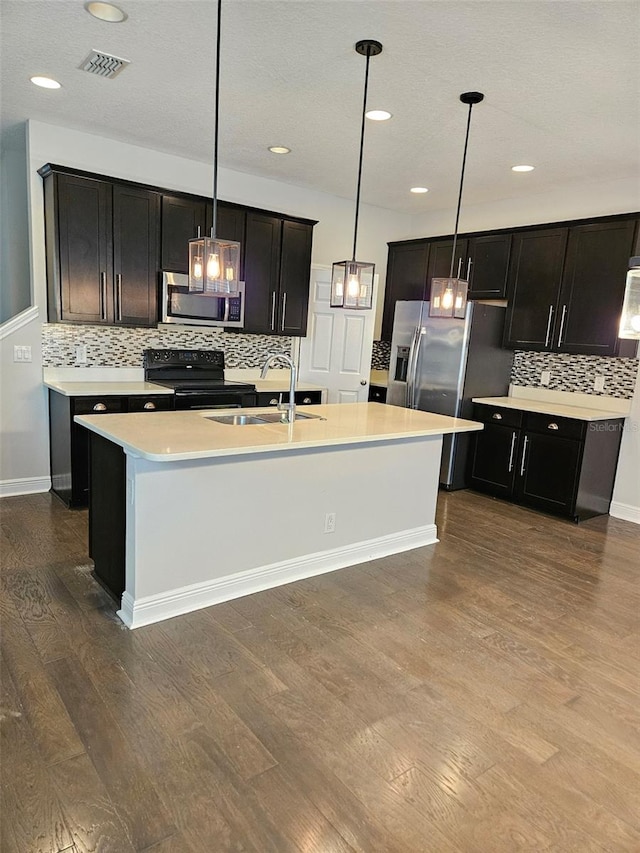 kitchen featuring stainless steel appliances, a sink, dark wood-style flooring, decorative backsplash, and light countertops