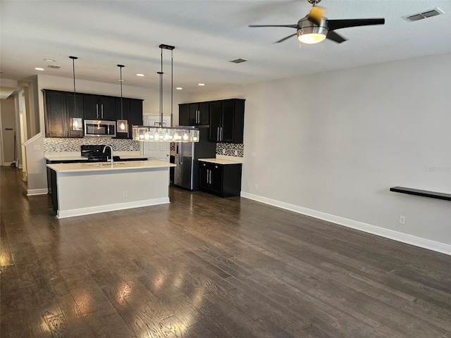 kitchen featuring stainless steel appliances, ceiling fan, light countertops, backsplash, and dark cabinetry