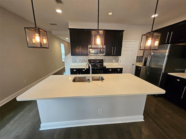 kitchen with appliances with stainless steel finishes, a sink, backsplash, light countertops, and dark wood finished floors