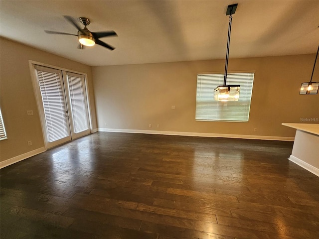 unfurnished dining area featuring dark wood-style flooring, baseboards, and a ceiling fan