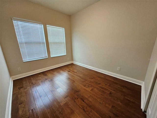 empty room with dark wood-style floors and baseboards