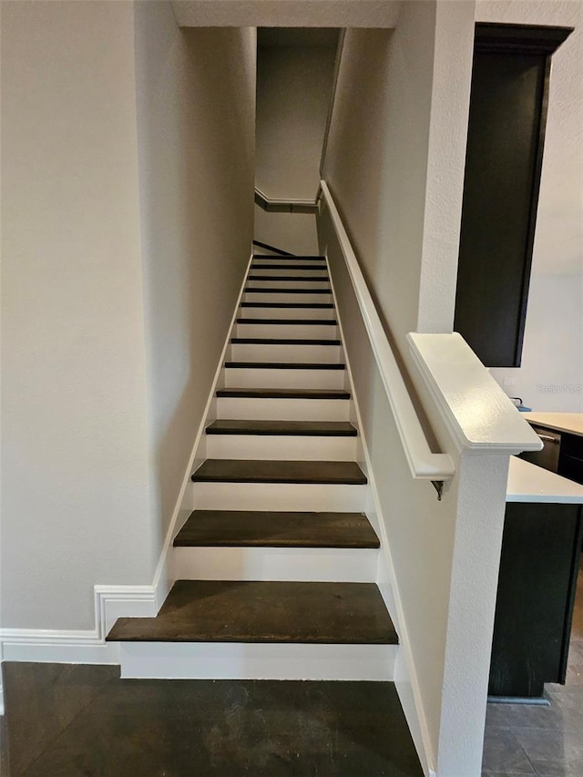 staircase with baseboards and concrete floors