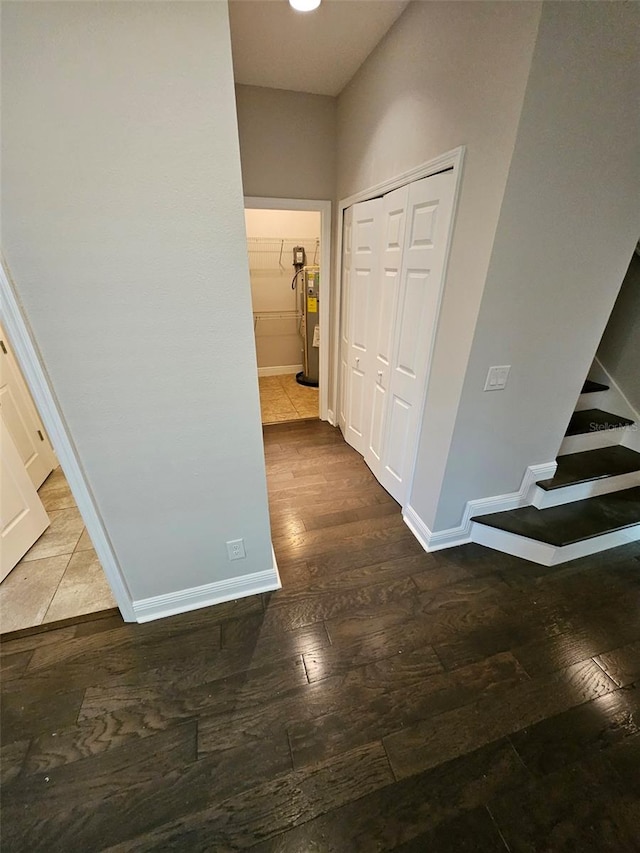 corridor with water heater, hardwood / wood-style flooring, baseboards, and stairs
