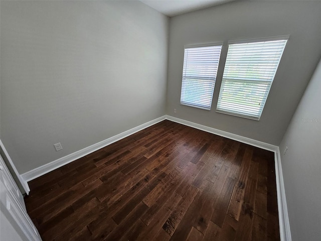 empty room featuring dark wood-style floors and baseboards