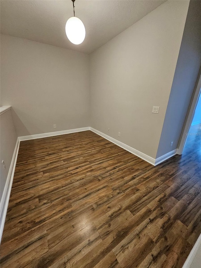 unfurnished room with dark wood-style floors and baseboards