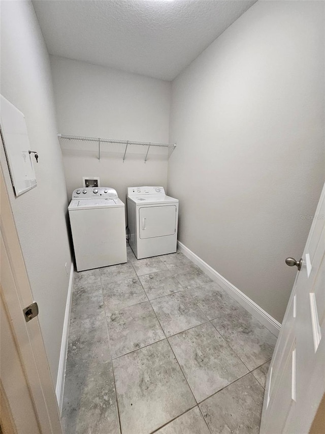 washroom featuring washer and dryer, baseboards, a textured ceiling, and tile patterned floors