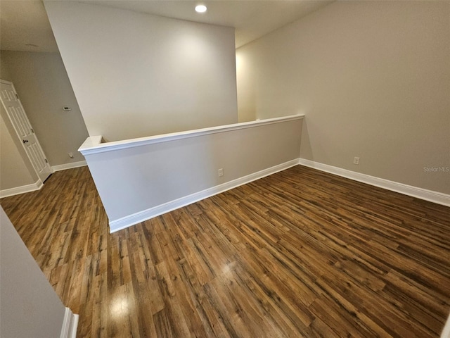 spare room with dark wood-type flooring, baseboards, and recessed lighting