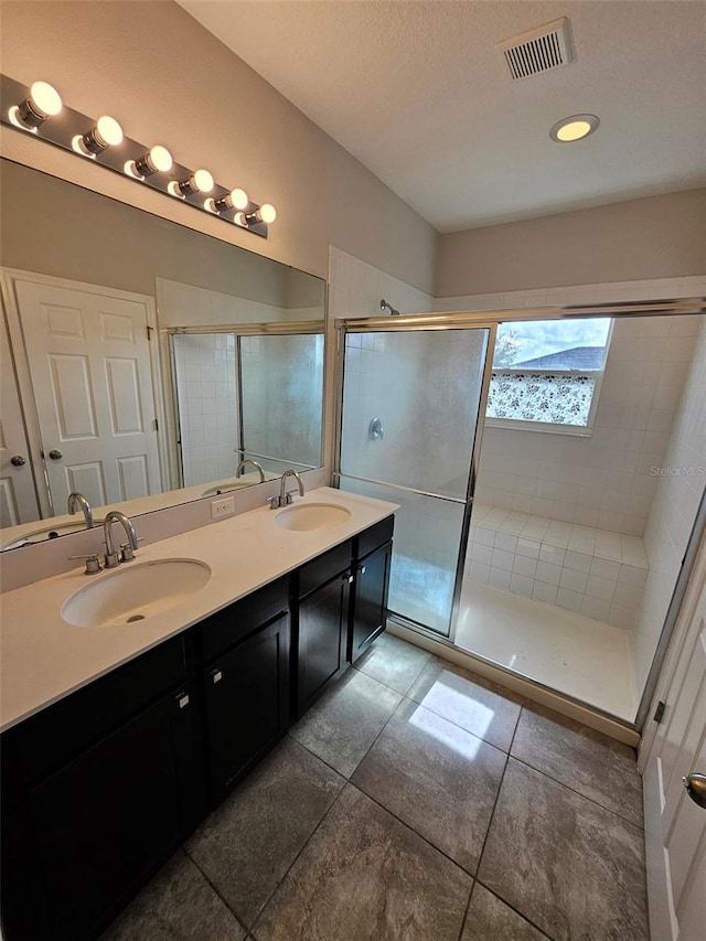 full bathroom with a shower stall, double vanity, and tile patterned floors