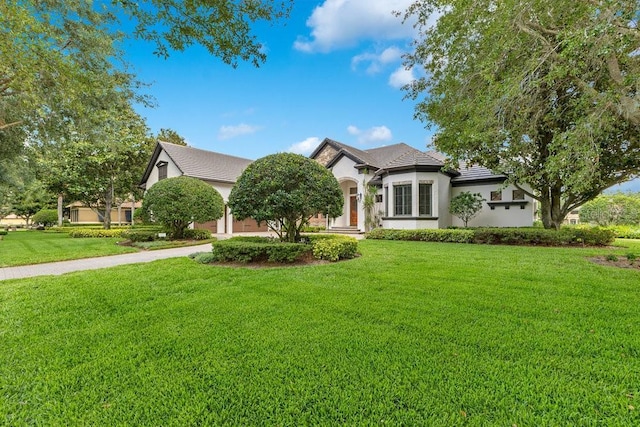 view of front facade with a front lawn, stucco siding, and a tile roof