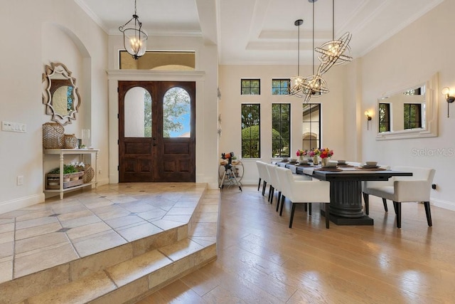 entrance foyer with a chandelier, ornamental molding, baseboards, hardwood / wood-style floors, and a tray ceiling