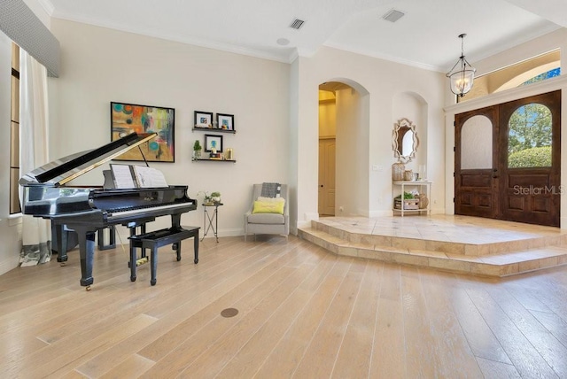 foyer entrance featuring arched walkways, wood-type flooring, baseboards, and ornamental molding